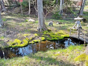 A pond with moss, a wooden bridge, and a stone lantern. - 6 Person Holiday Home in Djurhamn (Fågelbrolandet)