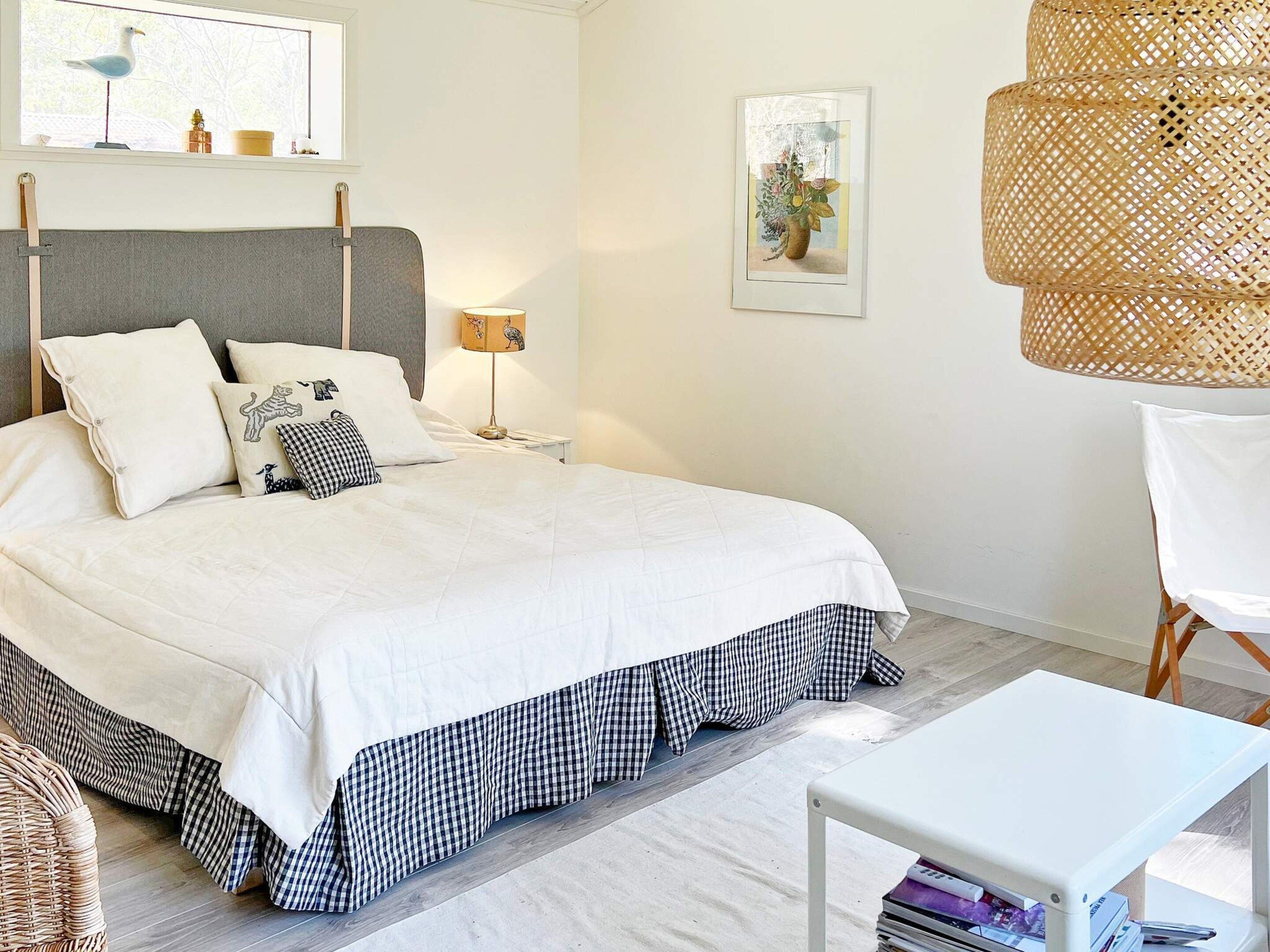 A neatly arranged bedroom with a bed, bedside table, lamp, and a chair.