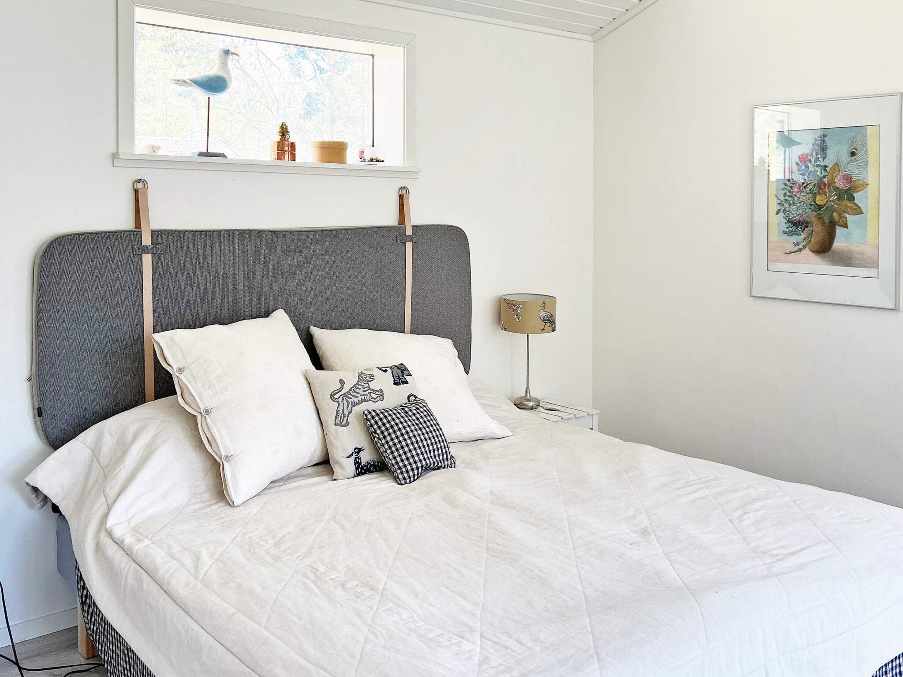 A bed with a grey headboard, white bedding, and decorative pillows.