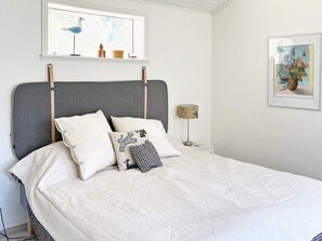 A bed with a grey headboard, white bedding, and decorative pillows. - 6 Person Holiday Home in Djurhamn (Fågelbrolandet)