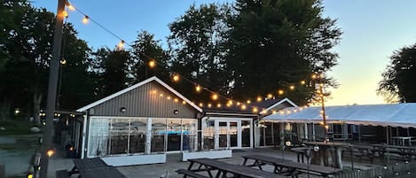 A wooden fence, picnic tables, and string lights.
