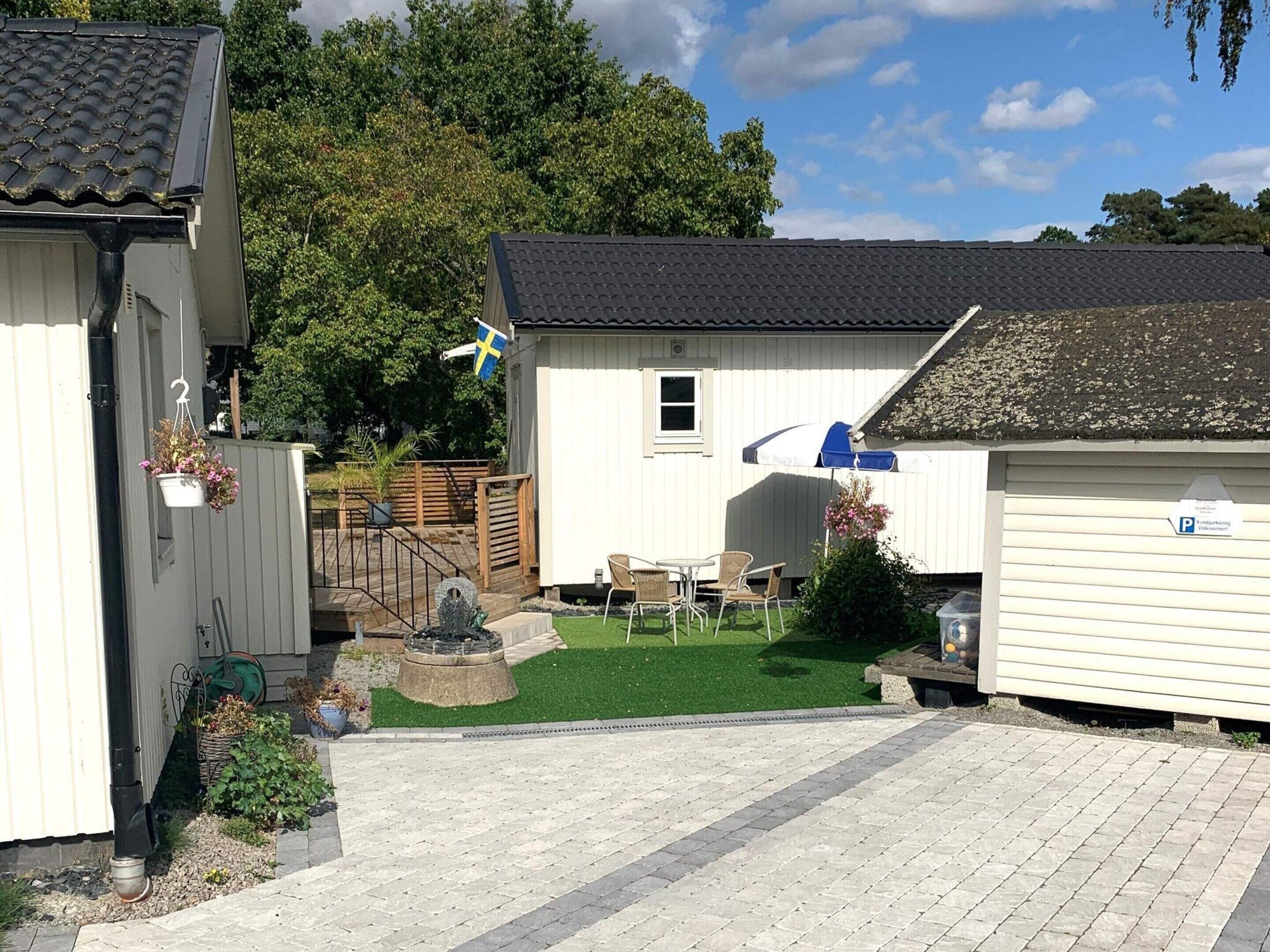 Ein kleines, eingeschossiges Gebäude mit einem Ziegeldach, einer Flagge und einer gepflasterten Terrasse mit Gartenmöbeln.