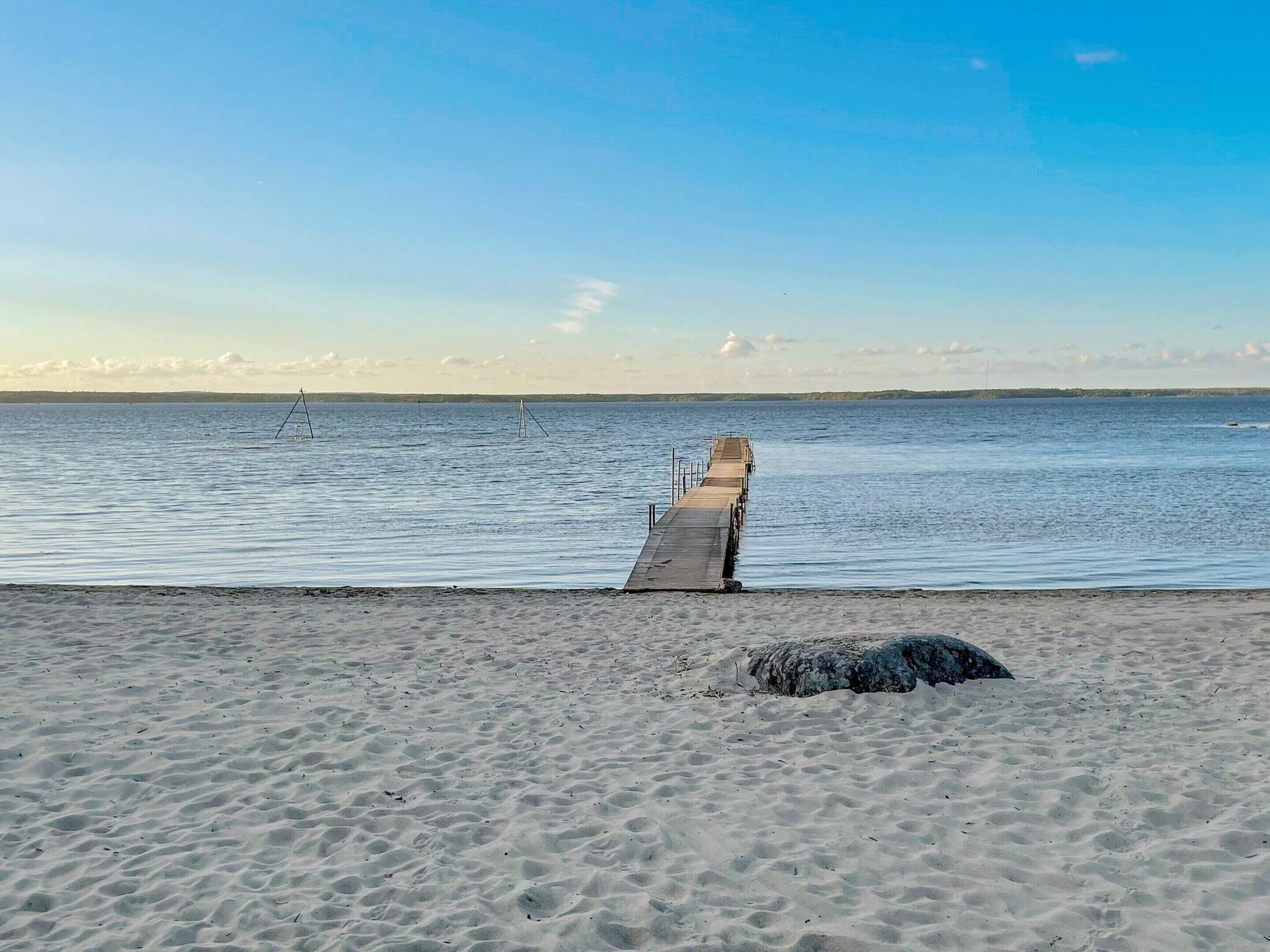 A sandy beach with a wooden pier extending into calm waters.