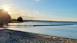 A beach with a wooden pier extending into calm water, surrounded by trees and a clear sky. - 4 Star Holiday Home in Solvesborg (Sölvesborg)