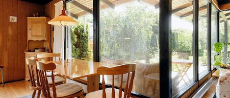 A dining area with wooden furniture and large windows.