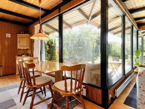 Un comedor con mobiliario de madera y ventanas amplias.