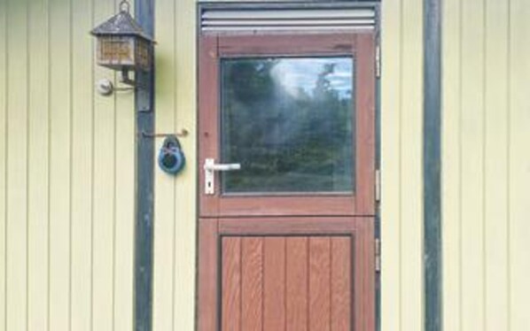 A wooden door with a window, a doorbell, and a wall-mounted light fixture. - 7 Person Holiday Home in Karrebaeksminde (Karrebæksminde)