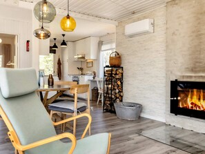 Una sala de estar moderna con chimenea, piso de madera y un comedor con mesa y sillas.