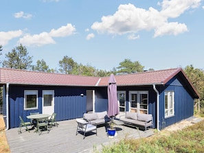 A blue building with a red roof, a patio with outdoor furniture, and a large umbrella. - 6 Person Holiday Home in Albaek (Aalbaek)