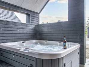 A hot tub with a bottle of beer and glasses, surrounded by wooden walls and a window. - 5 Star Holiday Home in Romo (Rømø)