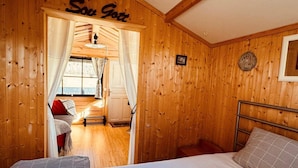 A cozy wooden room with a bed, a small table, and a window with curtains. - 3 Person Holiday Home in Munkforss (Munkfors)