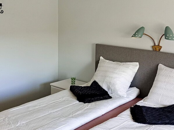 A neatly made bed with white and black pillows, a grey headboard, and a small bedside table with a green glass. - 4 Star Holiday Home in Norrtalje (Norrtälje)