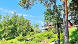 A serene lakeside setting with a small wooden structure, surrounded by lush greenery and tall trees. - 4 Star Holiday Home in Norrtalje (Norrtälje)