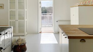 A kitchen with white cabinets, a wooden countertop, and a view to a balcony. - 4 Star Holiday Home in Norrtalje (Norrtälje)