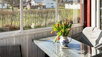 A conservatory with a glass table, a chair, and a vase of tulips.