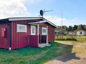 A red wooden cabin with a satellite dish, a door, and a small porch. - 6 Person Holiday Home in Laholm (Skummesloevsstrand)