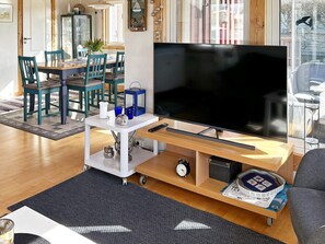 A living room with a flat-screen TV, a coffee table, a sofa, and a dining area with chairs and a table. - 6 Person Holiday Home in Laholm (Skummesloevsstrand)