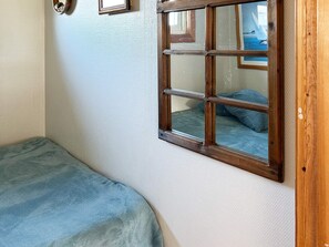 A room with a single bed, a window with a view of the sea, and a wall-mounted picture frame. - 6 Person Holiday Home in Laholm (Skummesloevsstrand)