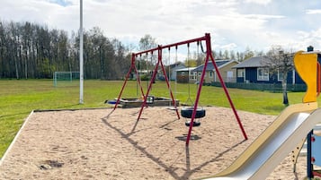 A playground with a swing set, tire swings, and a slide.