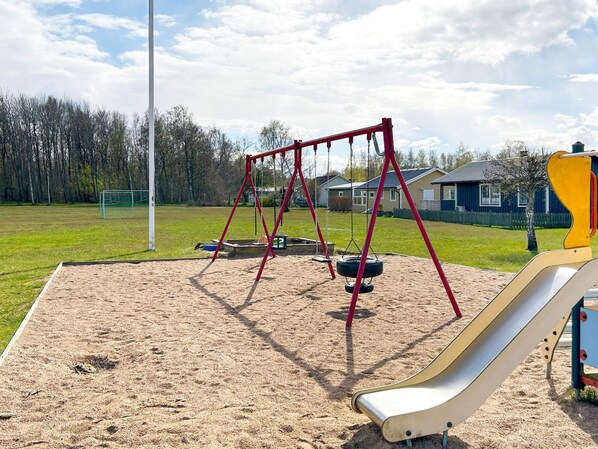 A playground with a swing set, tire swings, and a slide.