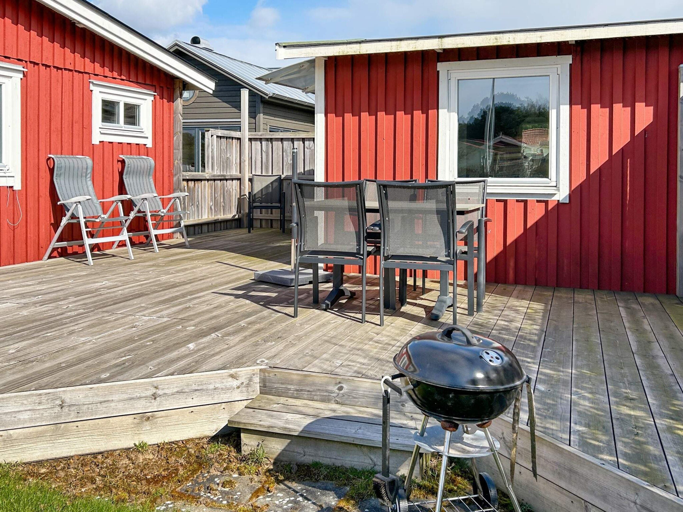 Een rood gebouw met een terras, zitplaatsen buiten en een barbecue.