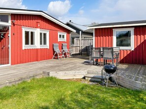 A red building with a wooden deck, two windows, and a barbecue grill. - 6 Person Holiday Home in Laholm (Skummesloevsstrand)