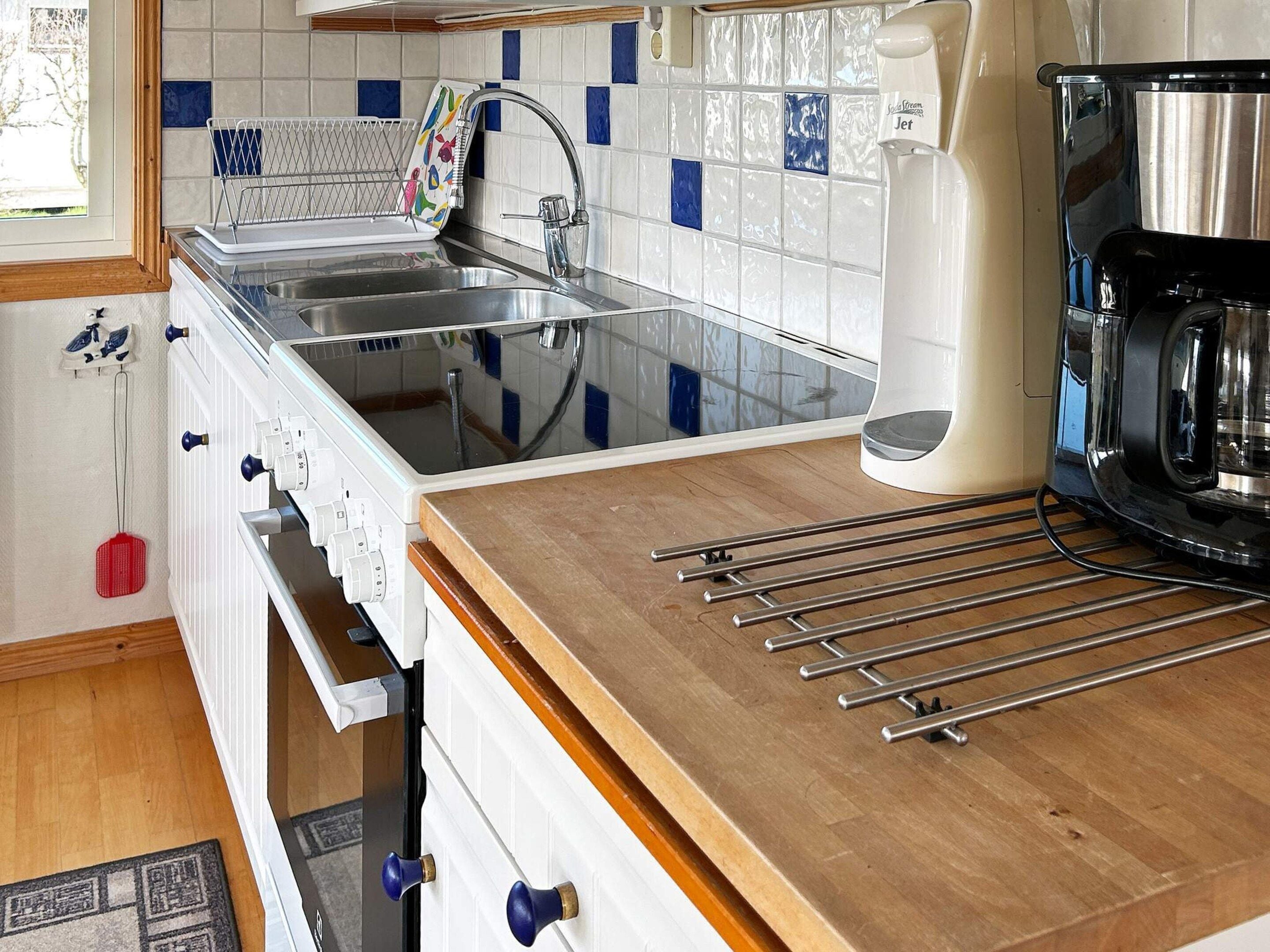 A kitchen with a sink, stove, and a coffee maker.