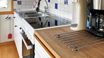 A kitchen with a sink, stove, and a coffee maker.