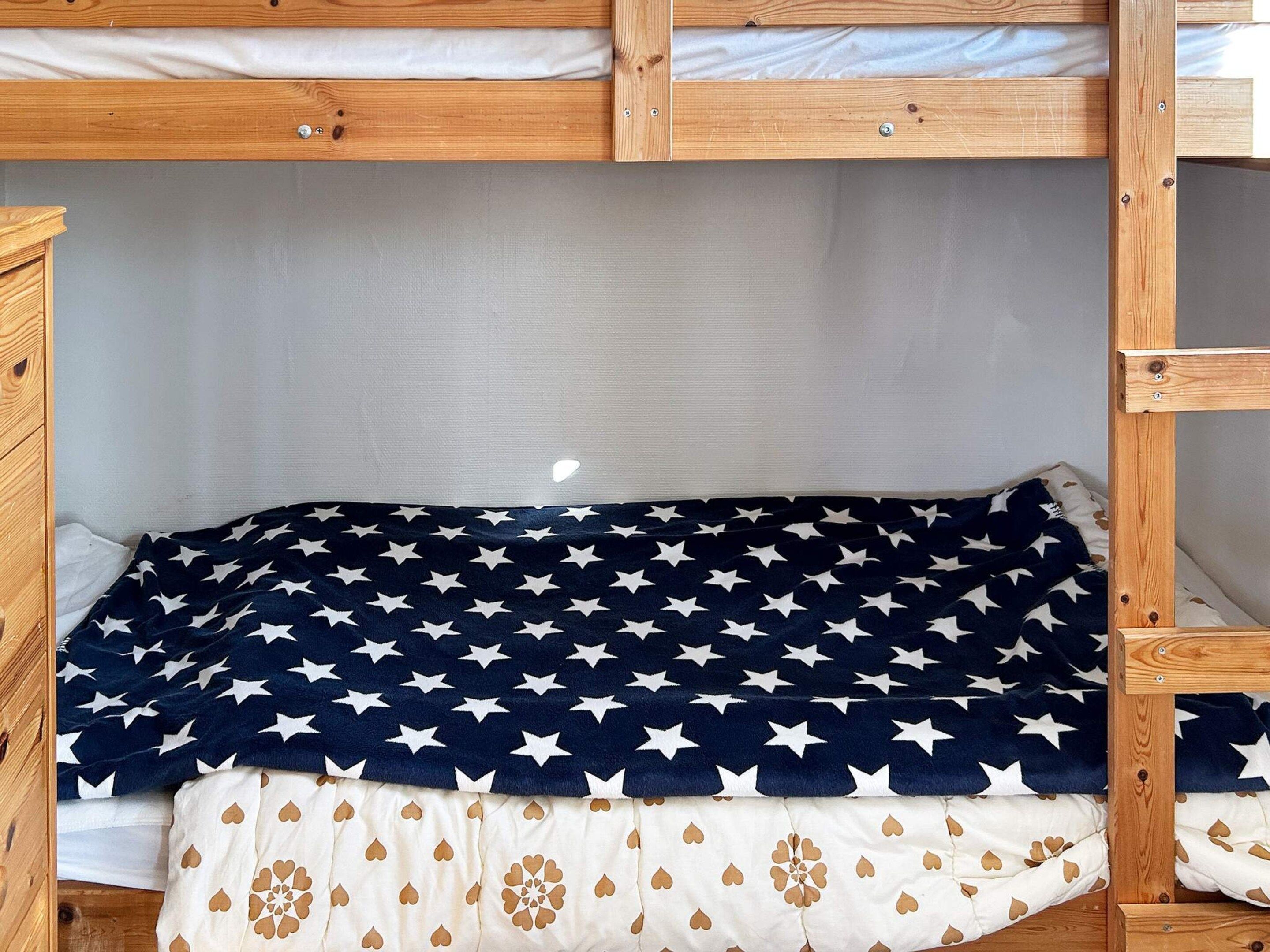 A bunk bed with a star-patterned blanket and a heart-patterned pillow.