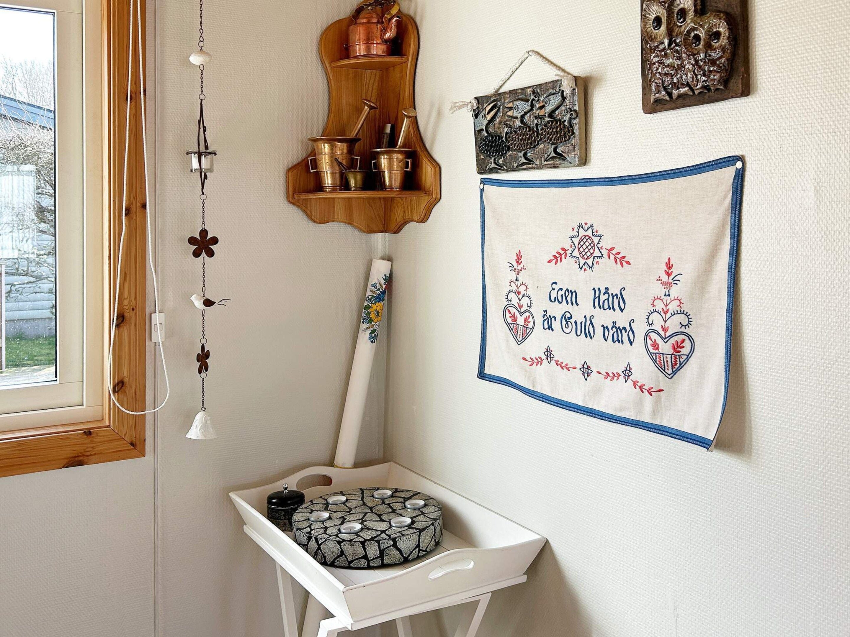 Une salle de bain avec une étagère en bois sur laquelle sont posés des récipients en métal, une serviette accrochée au mur et un élément décoratif mural.