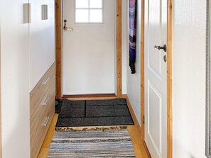 Um corredor com piso de madeira, tapete de entrada, carpete e porta com janela.