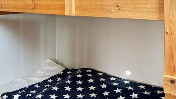 A bunk bed with a white mattress and a navy blanket with white stars.
