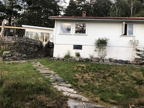 A white house with a stone pathway leading to the front door, surrounded by a stone wall and a small garden. - 4 Star Holiday Home in Uddevalla (Uddevalla)