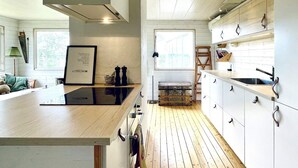 Une cuisine moderne avec un plancher en bois, des armoires blanches et une plaque de cuisson à induction noire.