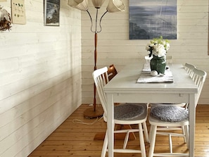 A dining area with a white table, chairs, a floor lamp, and a vase with flowers. - 4 Star Holiday Home in Uddevalla (Uddevalla)