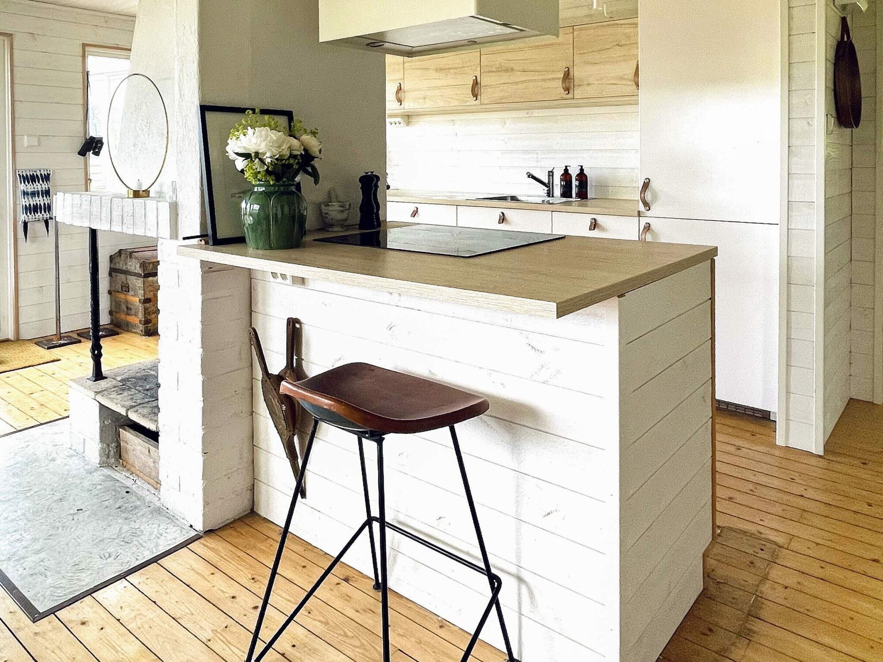 Een keuken met een houten aanrecht, een spoelbak en een barkruk.