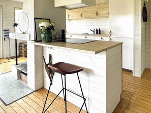 A kitchen with a wooden countertop, a sink, and a bar stool.