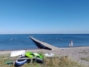 Une jetée s’avançant dans une mer calme, avec des bateaux et une personne debout à son extrémité.
