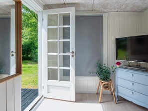 Une porte ouverte donnant sur un balcon où se trouve une télévision Samsung posée sur une commode.