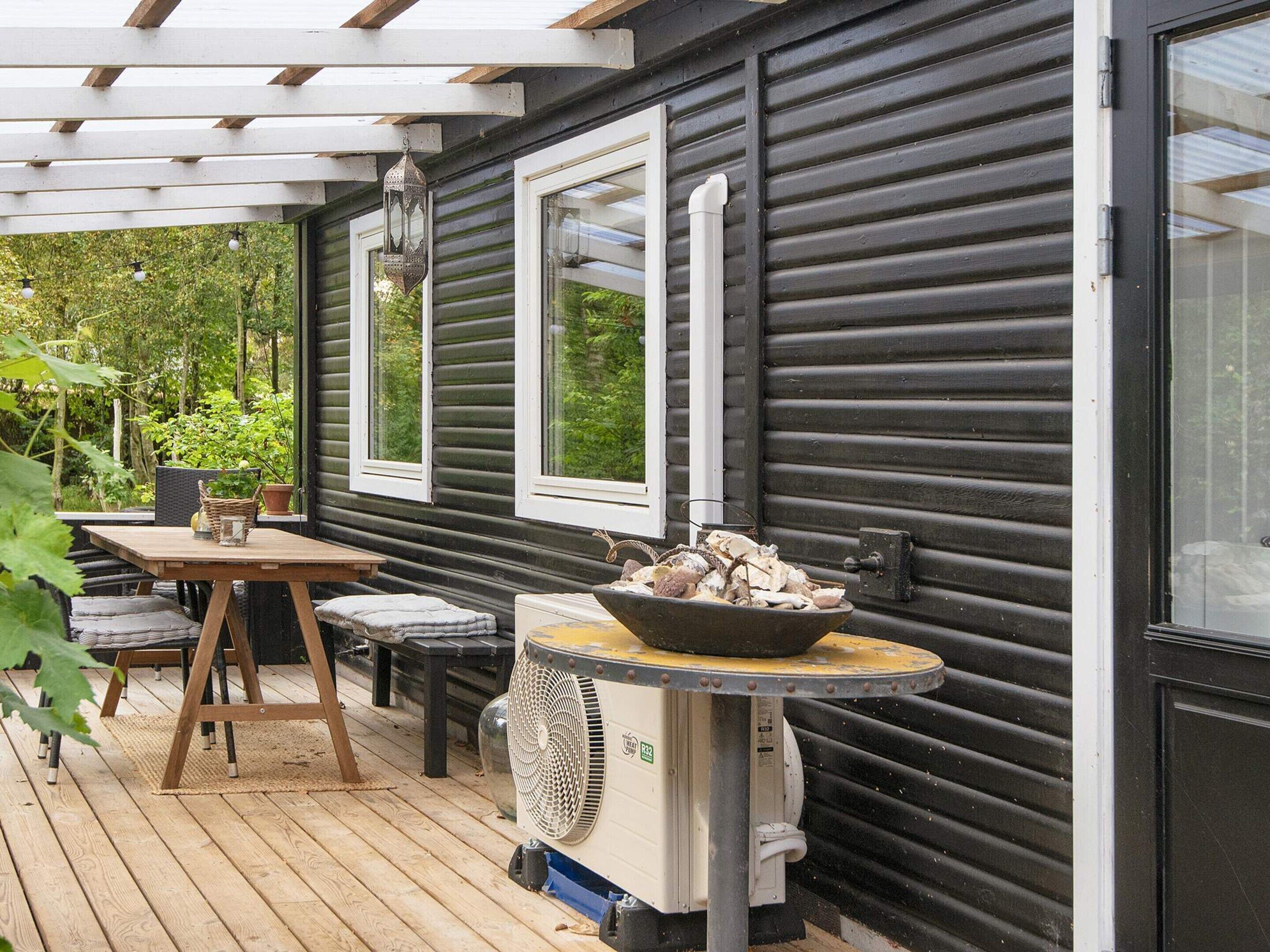 A wooden deck with a table and chairs, a fan, and a decorative bowl on a stand.