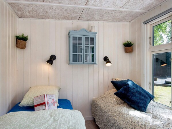 Une pièce confortable avec deux lits, une armoire bleue et des lampes fixées au mur.