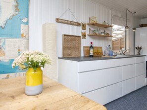 Una cocina con una isla de madera, armarios blancos, un mapa en la pared y un jarrón con flores sobre la encimera.