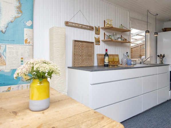 A kitchen with a wooden island, white cabinetry, a map on the wall, and a vase with flowers on the counter.