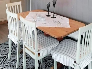 A dining area with a wooden table, white chairs with striped cushions, and a patterned rug. - 4 Star Holiday Home in Skjeberg (Sarpsborg)