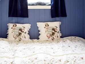A bed with a floral-patterned bedspread and two decorative pillows with vintage designs. - 4 Star Holiday Home in Skjeberg (Sarpsborg)