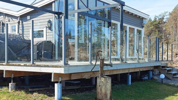 Et moderne hus med stor glasfacade, træterrasse og garage.