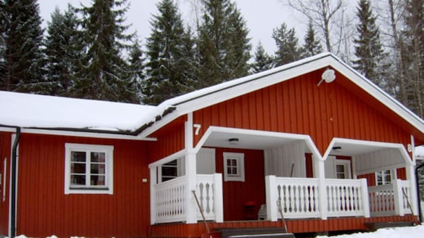 A red wooden house with a white porch and snow-covered surroundings. - 4 Person Holiday Home in Torsby (Torsby)