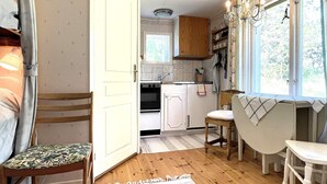 A cozy kitchen with wooden cabinets, a built-in oven, a dining area with a table and chairs, and a window with a view of greenery. - 5 Person Holiday Home in Ydre (Österbymo)