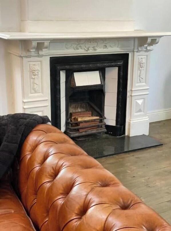 Cozy up by the traditional fireplace with a mantel and surround, paired with a comfortable leather sofa.