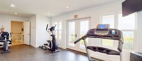Un gimnasio con cintas de correr, elíptica y bicicleta estática.